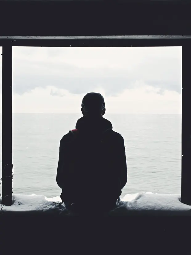 Someone sitting alone, looking out at the sea